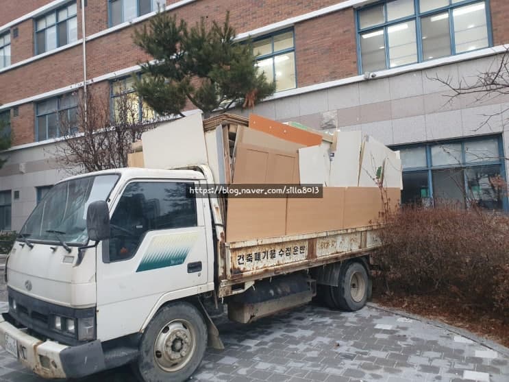 철거 자재를 적재한 신라환경 차량이 건물 앞에 서있는 모습