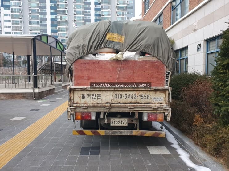건축폐기물을 적재하고 건물 앞을 나서는 신라환경 차량